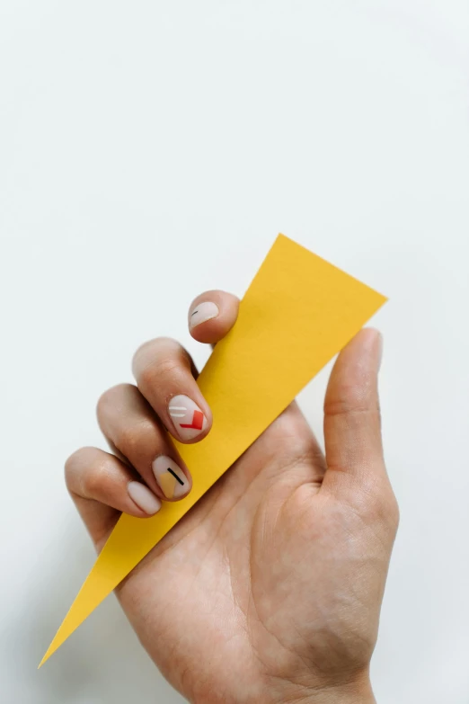 a person holding a piece of paper in their hand, nail art, yellow-orange, diagonal, graphic detail