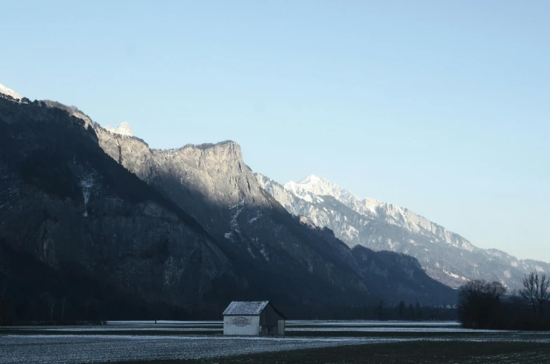 a small house in a field with mountains in the background, inspired by Peter Zumthor, pexels contest winner, minimalism, icy lake setting, early morning light, today\'s featured photograph 4k, white