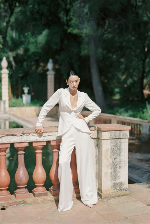 a woman in a white dress leaning on a railing, an album cover, inspired by Luis Paret y Alcazar, unsplash, renaissance, white suit and black tie, kiko mizuhara, androgynous person, in a garden