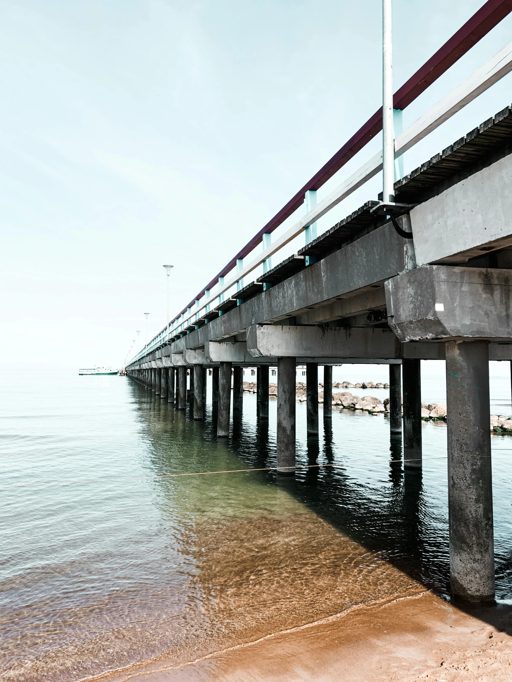 a long bridge over a body of water, unsplash, hyperrealism, capital of estonia, 2022 photograph, seaside, viewed from below