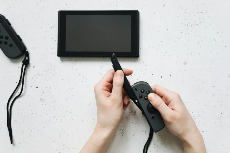 a person is holding a video game controller, a picture, unsplash, nintendo switch, all black matte product, digital pen and digital ink, black wired cables