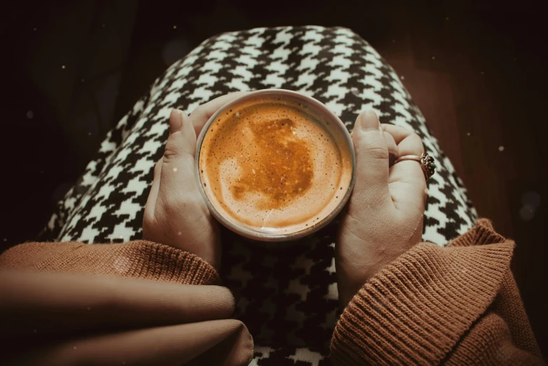 a person holding a cup of coffee in their hands, a photo, by Lucia Peka, trending on pexels, black and orange, cosy, retro stylised, chilly