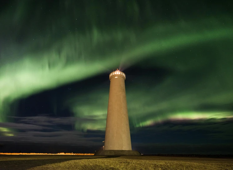 a light house sitting on top of a grass covered field, by Hallsteinn Sigurðsson, pexels contest winner, hurufiyya, aurora in the sky, view from below, national geohraphic, pillar