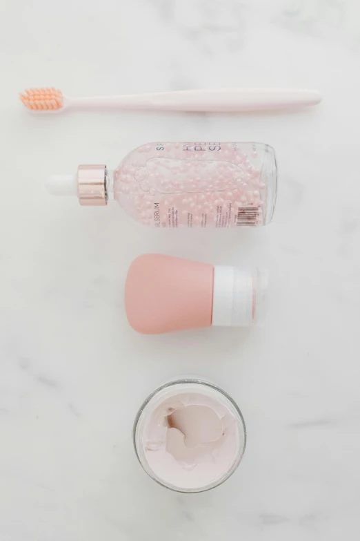 a couple of toothbrushes sitting on top of a counter, by Nicolette Macnamara, trending on pexels, rose quartz, bottle, silicone cover, miniature product photo