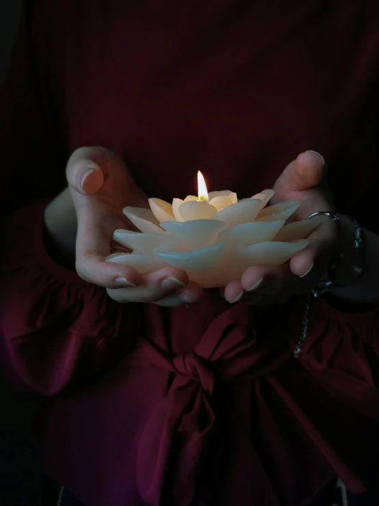 a woman holding a lit candle in her hands, inspired by Elsa Bleda, pexels, hurufiyya, large opaque blossoms, resin, centred, foam