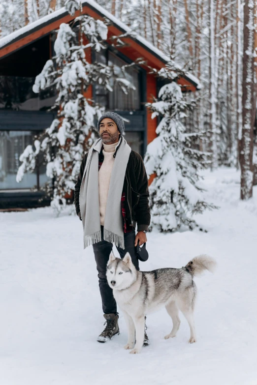 a man standing in the snow with a dog, a photo, by Julia Pishtar, pexels contest winner, donald glover, chalet, white and grey, holiday vibe