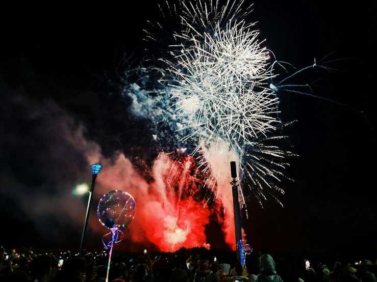 a crowd of people watching a fireworks display, by Lee Loughridge, pexels, hurufiyya, teal silver red, photo of the year, instagram post, red and blue back light