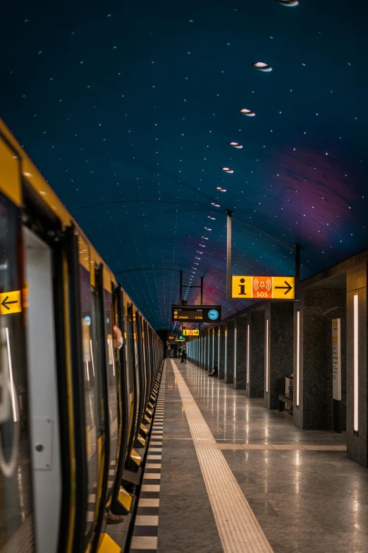 a train pulling into a train station at night, by Jens Søndergaard, unsplash contest winner, graffiti, yellow carpeted, blue lamps on the ceiling, 🚿🗝📝, underground metro