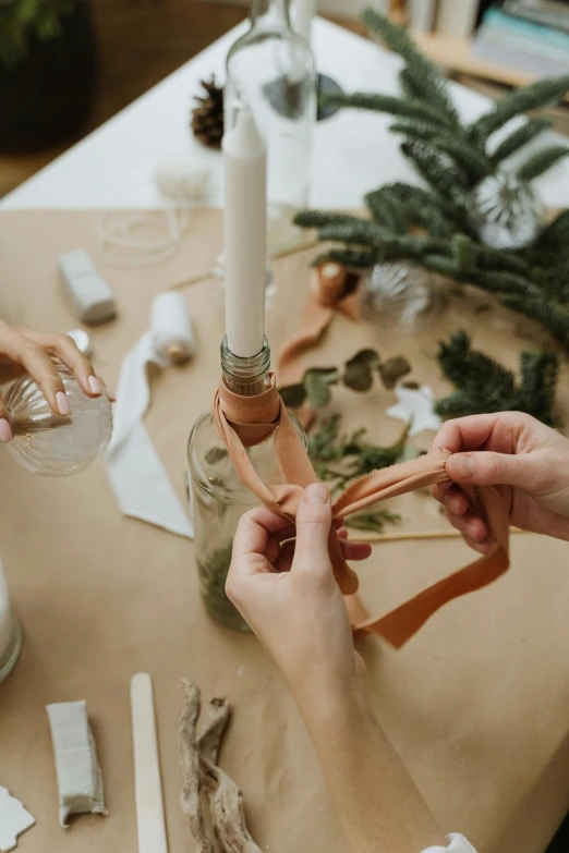 a couple of people that are sitting at a table, ribbon, holding a candle holder, blending, branches wrapped