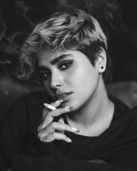a black and white photo of a woman smoking a cigarette, a black and white photo, by irakli nadar, trending on pexels, short platinum hair tomboy, indian, beautiful androgynous prince, cynthwave
