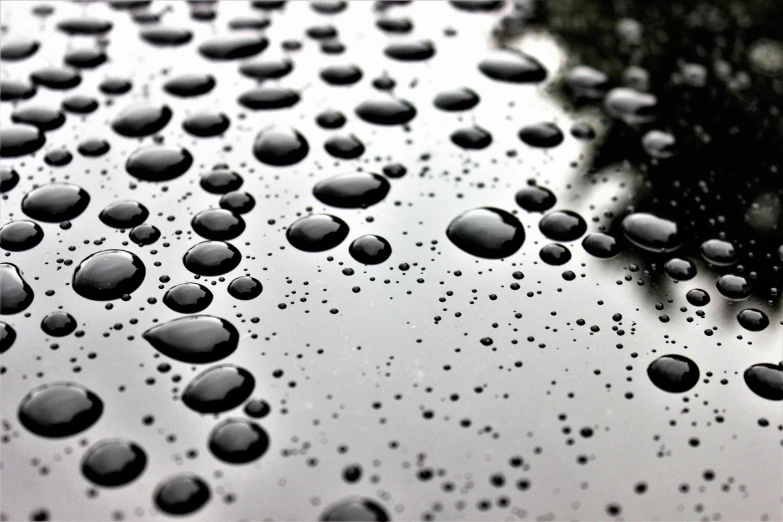 a close up of water droplets on the hood of a car, a stipple, pexels, photorealism, black roof, wet reflective ground, clouds on surface, low-angle