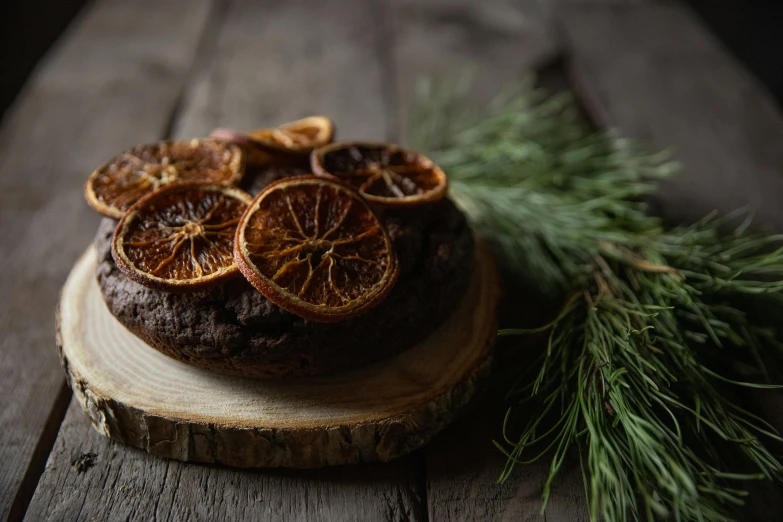 a cake sitting on top of a wooden table, by Jesper Knudsen, pexels contest winner, orange slices, black fir, organic ornament, dark chocolate hair colour