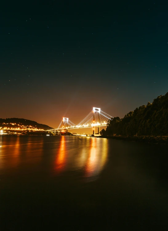 a bridge over a body of water at night, pexels contest winner, wales, golden cityscape, vallejo, ultrawide lens”