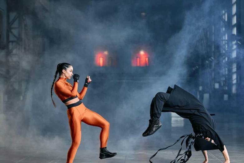 a couple of women standing next to each other on a stage, pexels contest winner, figuration libre, epic ninja suit, facing off in a duel, kylie jenner as catwoman, in orange clothes) fight