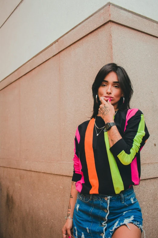 a woman standing in front of a wall talking on a cell phone, an album cover, by Giorgio Cavallon, trending on pexels, wearing a colorful coogi sweater, girl with black hair, hero pose colorful city lighting, peru