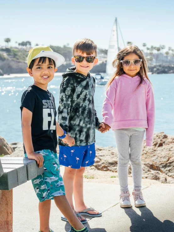 a group of young children standing next to a body of water, wearing sunglasses, katelynn mini cute style, street wear, slide show