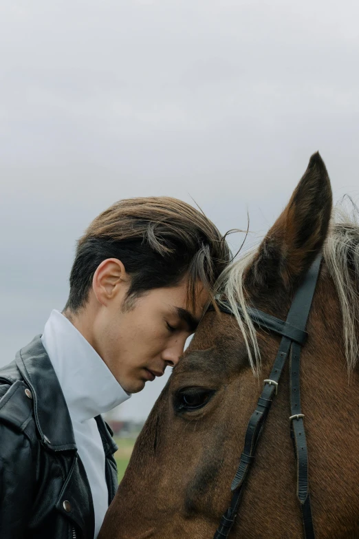 a man standing next to a brown horse, an album cover, inspired by Zhang Han, trending on unsplash, romanticism, prominent cheekbones, photographed for reuters, movie still of a tired, kazuya takahashi