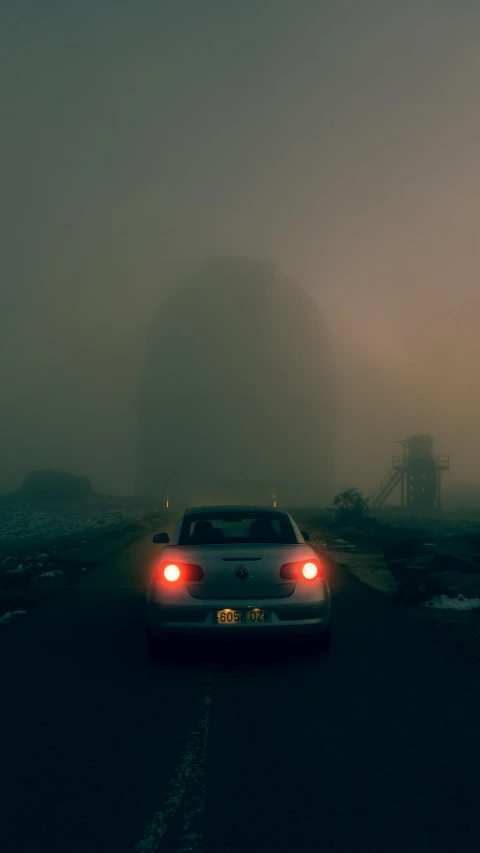 a car is driving on a foggy road, an album cover, inspired by Elsa Bleda, conceptual art, cinematic. by leng jun, ominous photo, dramatic lighting - n 9, rear-shot