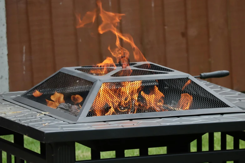 a fire pit with flames coming out of it, metal lid, square, easy to use, feature