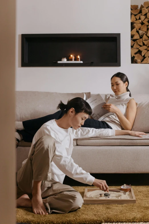 two women sitting on a couch playing a board game, inspired by Fei Danxu, clean minimalist design, asian male, cosy vibes, candle lit