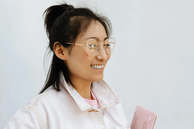 a close up of a person holding a cell phone, by helen huang, pink glasses, smiling confidently, profile view, asian human