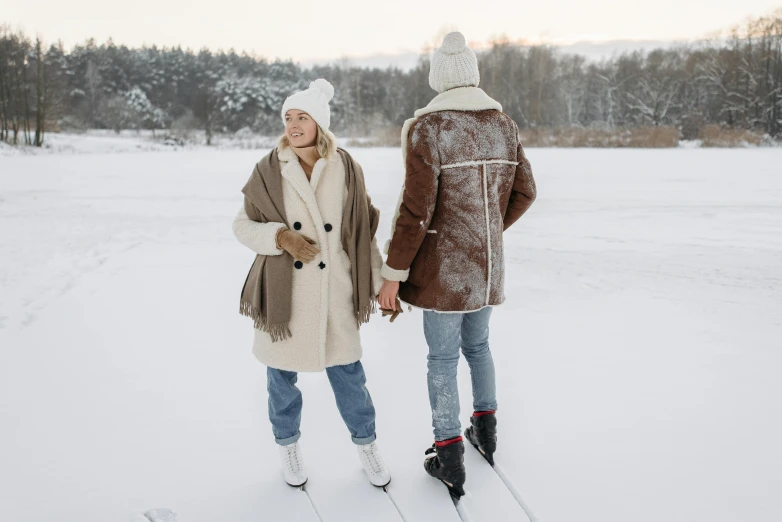 two people standing in the snow holding hands, by Eero Järnefelt, trending on pexels, standing on a skateboard, light brown coat, on a lake, wearing festive clothing