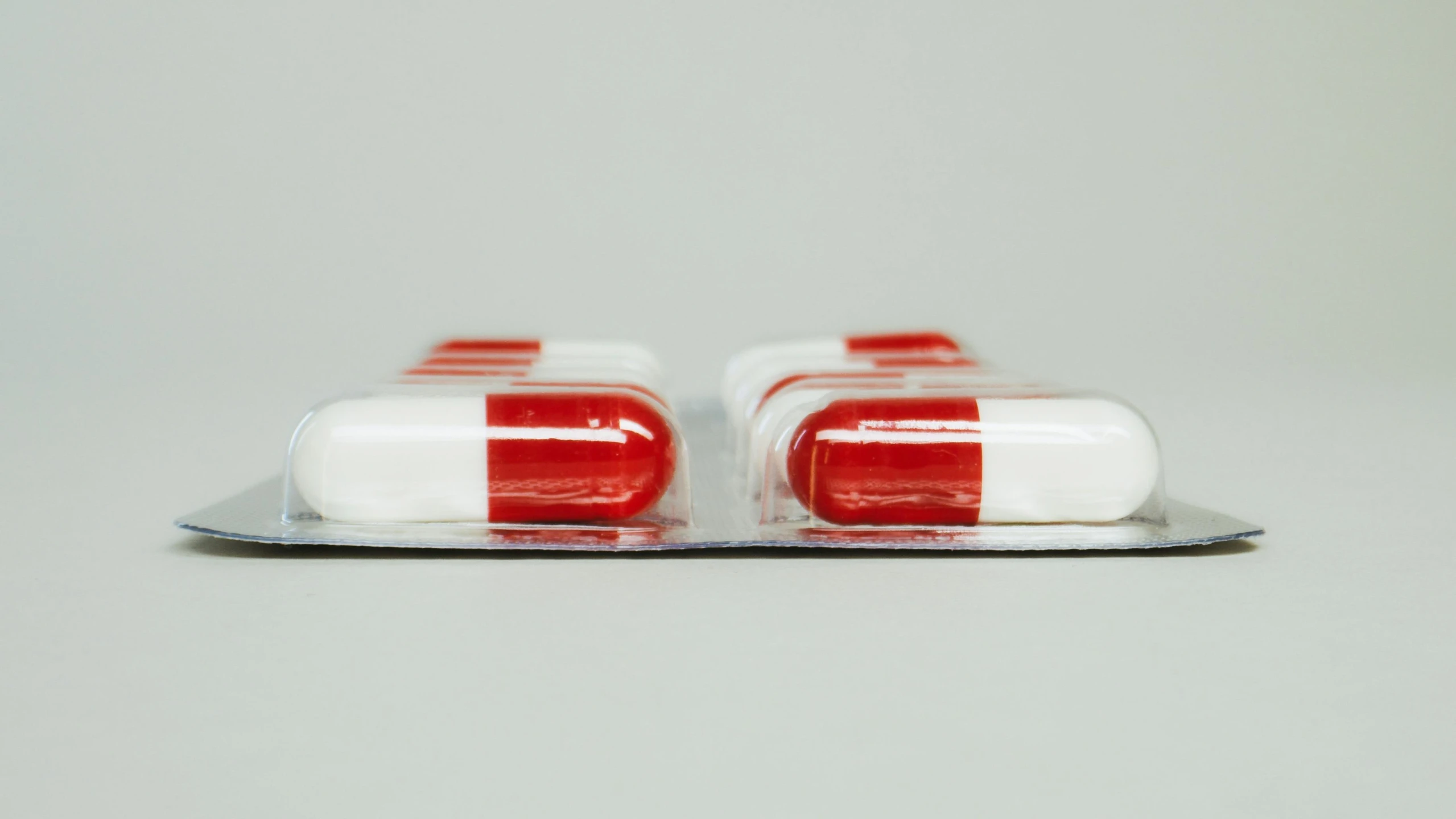 a couple of pills sitting on top of a tray, unsplash, hyperrealism, red stripe, side profile view, made of plastic, close-up shot from behind