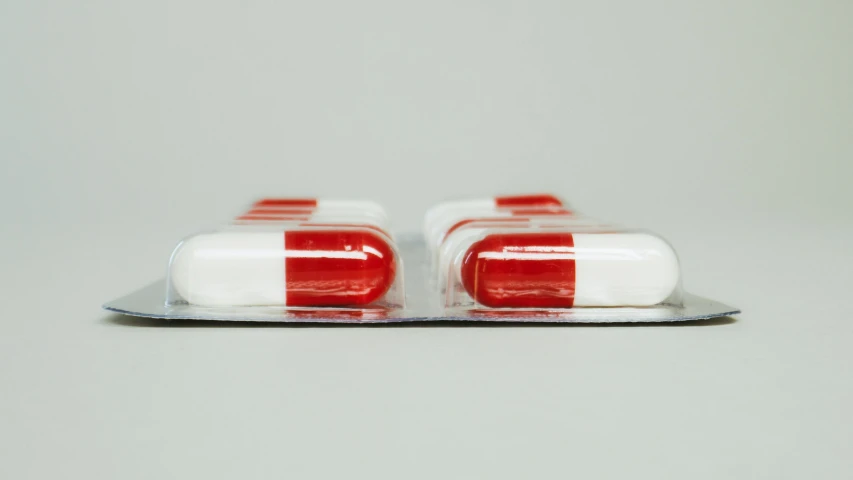 a couple of pills sitting on top of a tray, unsplash, hyperrealism, red stripe, side profile view, made of plastic, close-up shot from behind