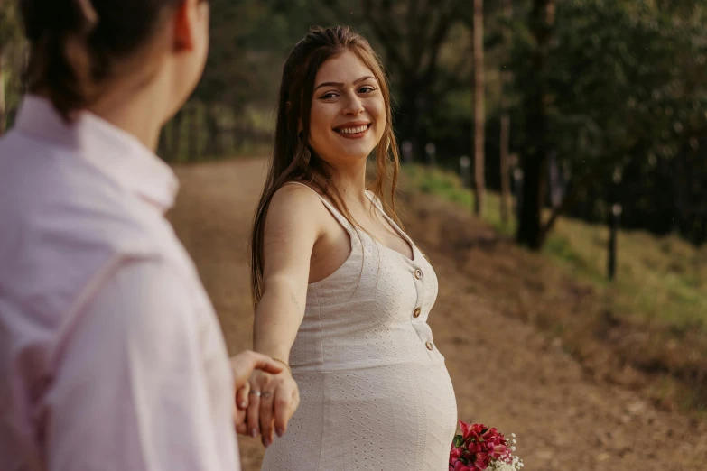 a pregnant woman standing next to a man on a dirt road, pexels contest winner, happening, woman with braided brown hair, welcoming grin, bump in form of hand, avatar image