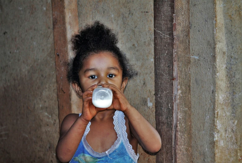 a little girl holding a bottle in front of her face, by Almada Negreiros, pexels contest winner, milk, madagascar, avatar image, blank