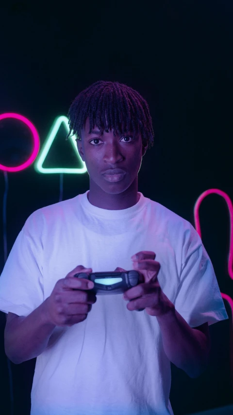 a man holding a video game controller in front of neon signs, pexels, afrofuturism, playboi carti portrait, ☁🌪🌙👩🏾, black teenage boy, in a black room