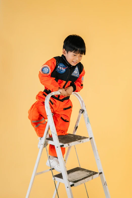 a little boy that is standing on a ladder, inspired by Liang Kai, pexels contest winner, in a space cadet outfit, official product photo, orange gi, space craft