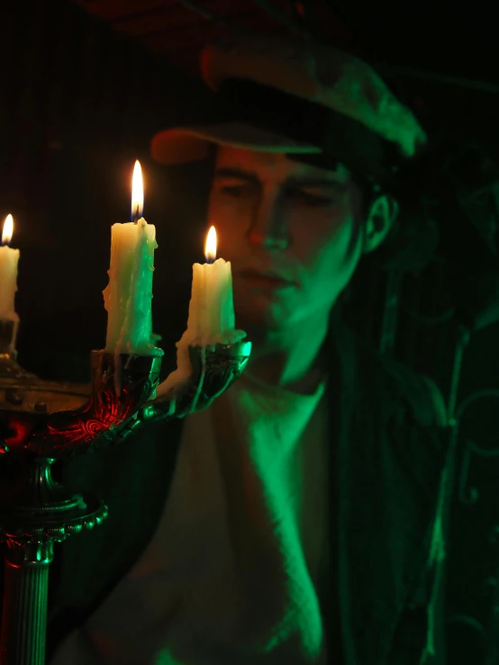 a man holding a candelab with lit candles, inspired by Nan Goldin, vanitas, red and green lighting, **cinematic, on a candle holder, wizard hat cinematic lighting