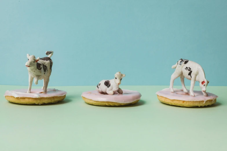 three figurines of dogs on top of doughnuts, by Sylvia Wishart, milk, trending on dezeen, cow hoof feet, sea of parfait