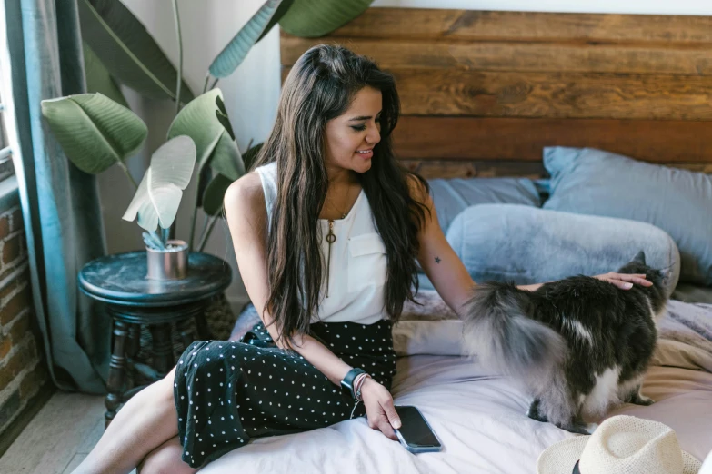 a woman sitting on a bed petting a cat, trending on pexels, female with long black hair, aussie, profile image, attractive photo