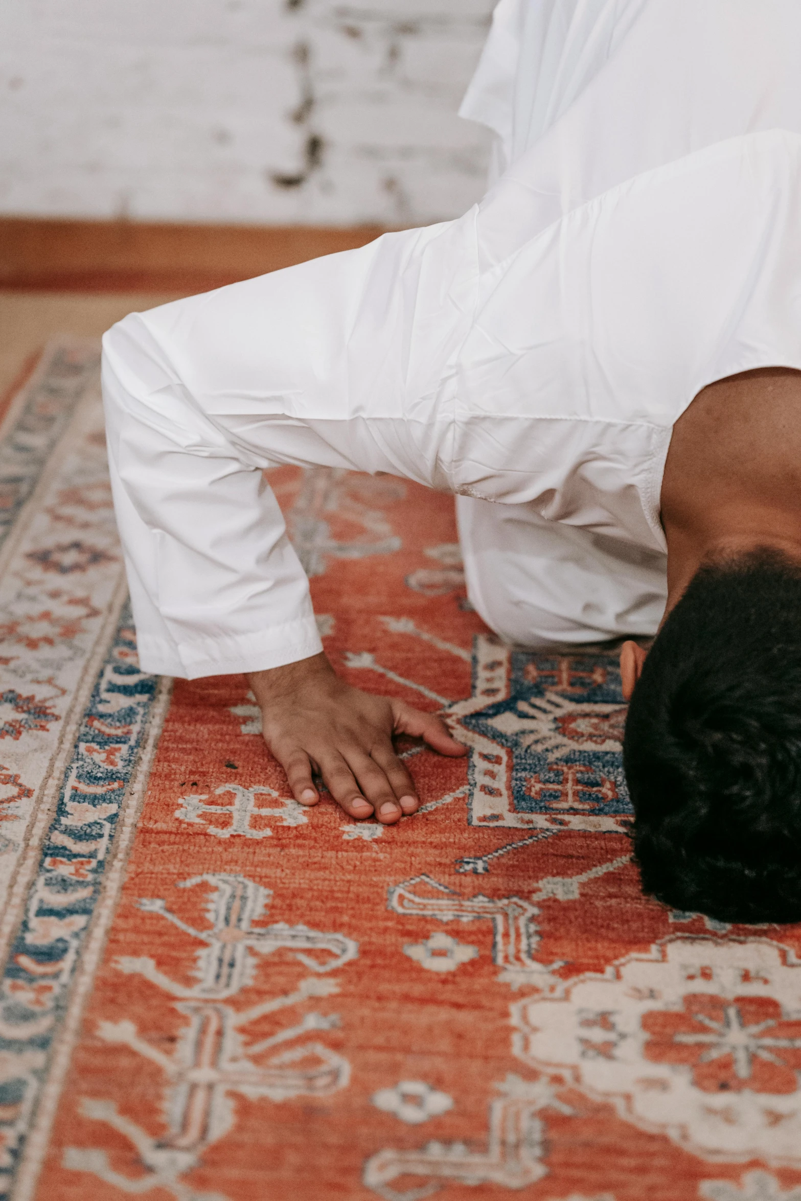 a man is doing a handstand on a rug, by Carey Morris, pexels contest winner, hurufiyya, kneeling in prayer, muslim, bent over posture, indoor setting