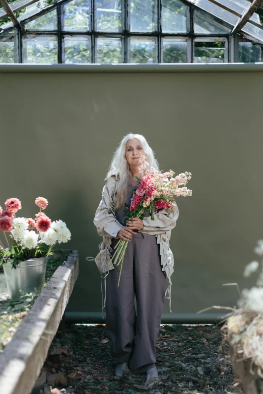 a woman holding a bunch of flowers in a greenhouse, a portrait, by Sara Saftleven, unsplash, long silver hair, die antwoord yolandi visser, wearing a grey robe, artist wearing overalls