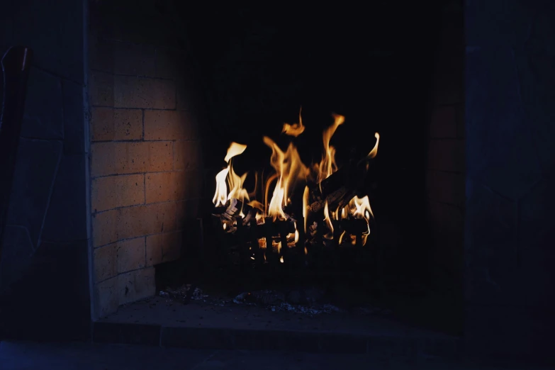 a fire burns in a fireplace in a dark room, inspired by Elsa Bleda, taken with kodak portra, lachlan bailey, woodfired, on blue fire