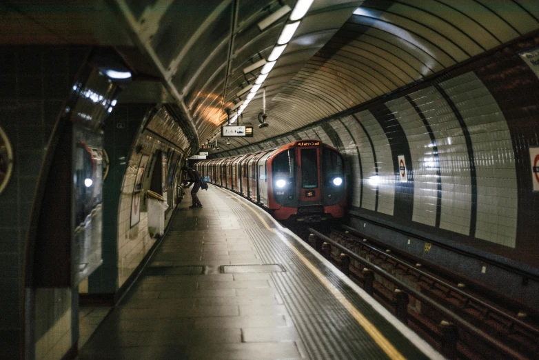 a train traveling through a tunnel next to a platform, unsplash, down in the sewers of london, 🚿🗝📝