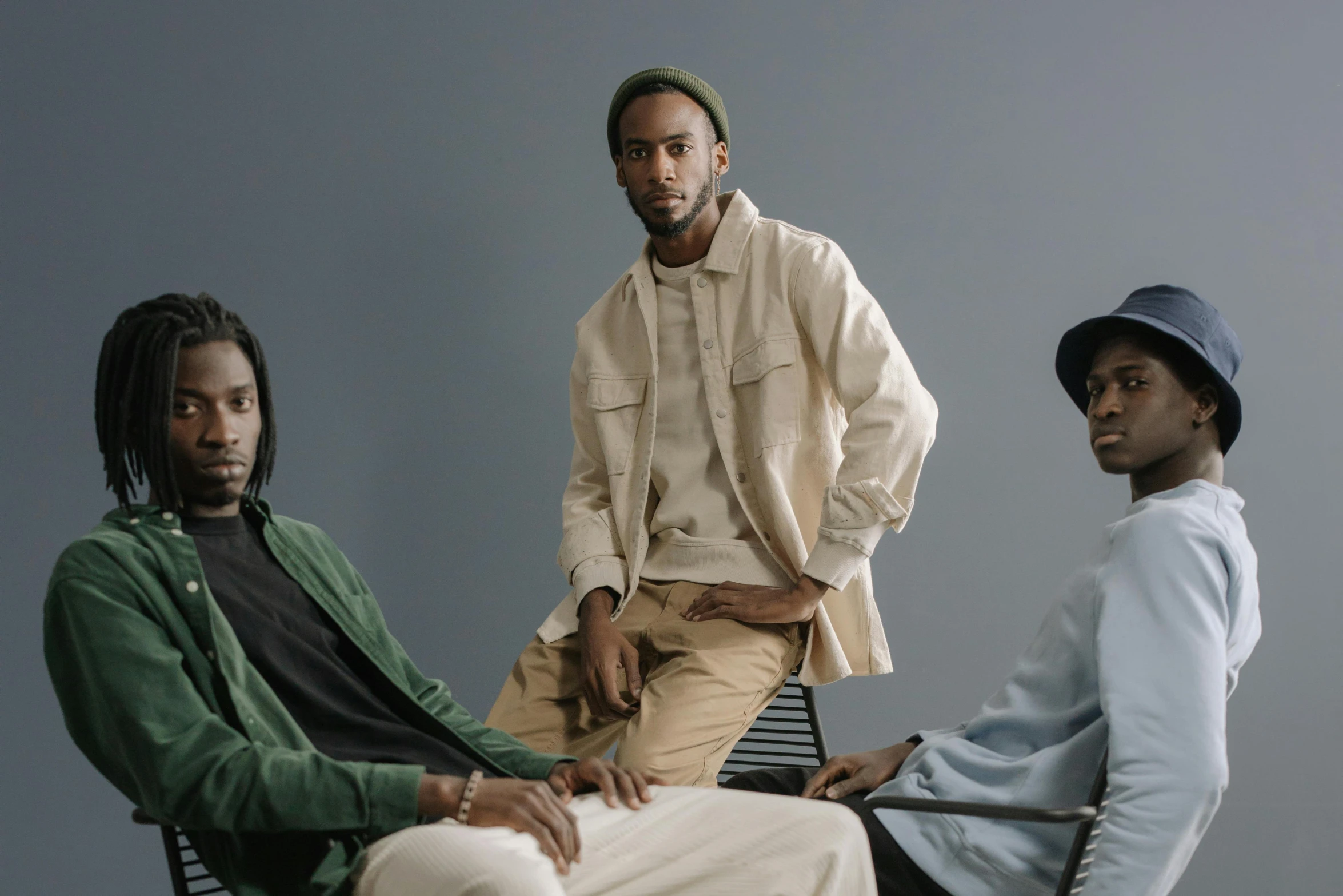 three men sitting next to each other on a chair, inspired by Barthélemy Menn, unsplash, black arts movement, green and brown clothes, khakis, model posing, ( ( dark skin ) )