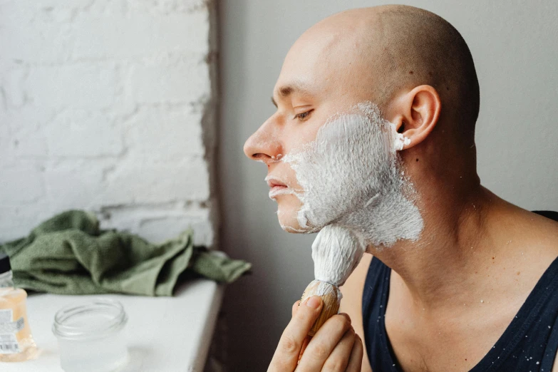 a bald man shaving his face with a razor, by Emma Andijewska, trending on pexels, renaissance, white facepaint, square facial structure, profile image, covered in white flour