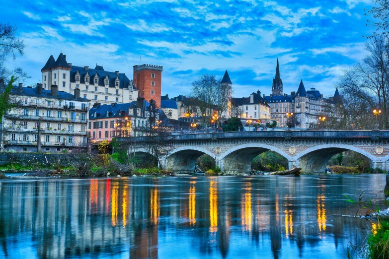 a bridge over a river with buildings in the background, pexels contest winner, art nouveau, rennes - le - chateau, vibrant glow, villages castles, early evening