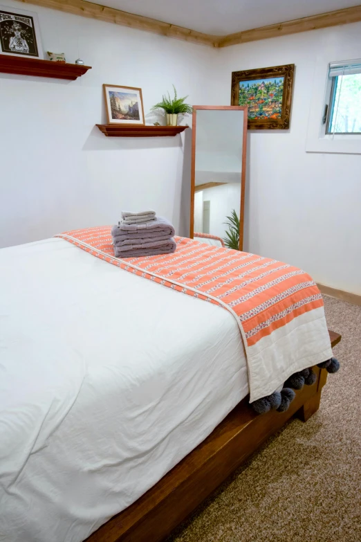 a bed room with a neatly made bed and a mirror, bright towels, blanca alvarez, profile image, health spa and meditation center