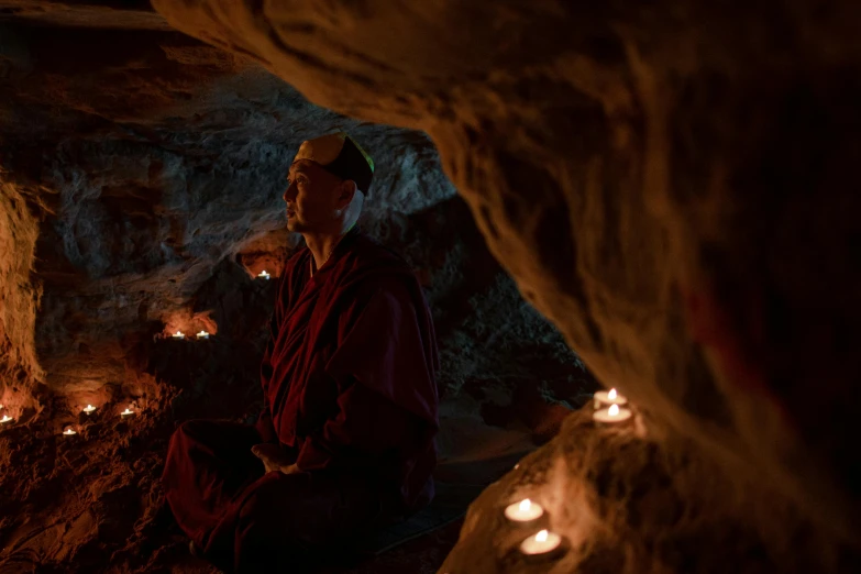 a monk sitting in a cave surrounded by candles, lpoty, documentary photo, fan favorite, full frame image