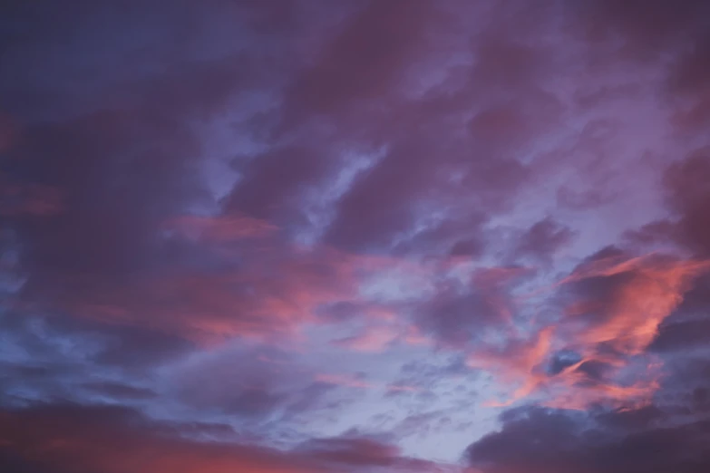 a group of people standing on top of a beach under a cloudy sky, a picture, unsplash, romanticism, barely lit warm violet red light, close - up photograph, looking up onto the sky, dusk