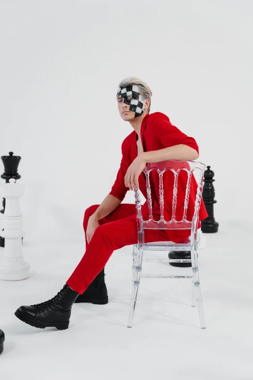 a man sitting on top of a chair next to chess pieces, an album cover, inspired by Julian Allen, trending on pexels, wearing red attire, cai xukun, non binary model, invisible man