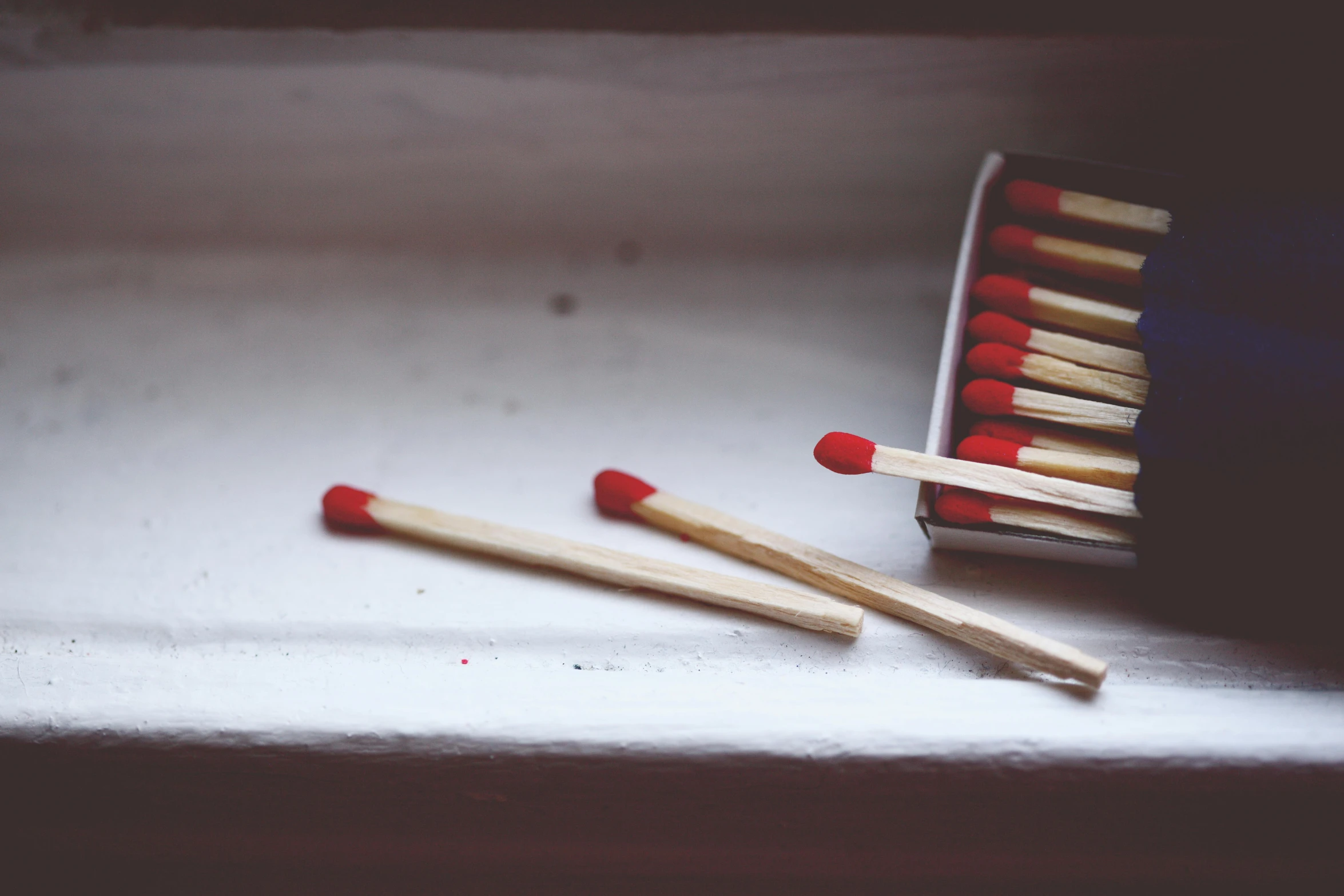 a box of matches sitting on top of a window sill, by Emma Andijewska, pexels contest winner, auto-destructive art, red and white, small fire, instagram post, faded and dusty