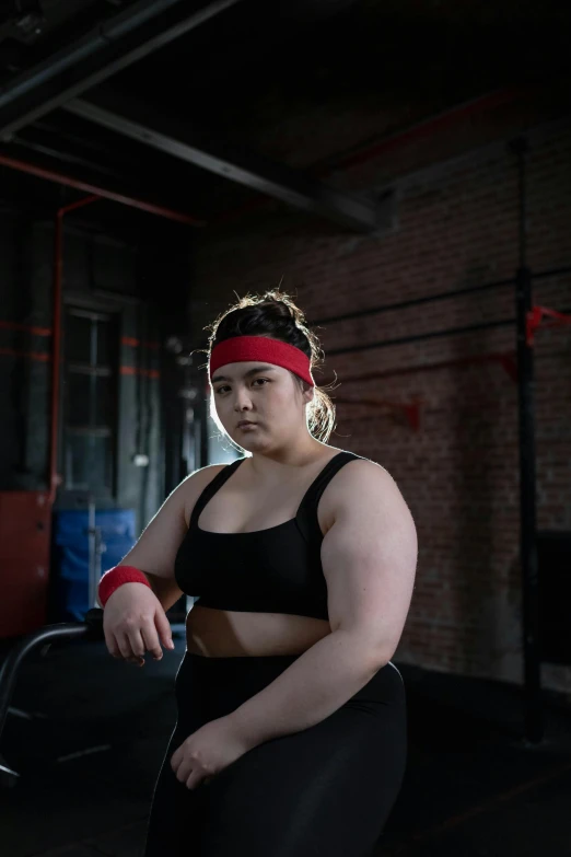 a woman in a black top and a red headband, by Sam Black, trending on pexels, an obese, in the high school gym, non binary model, chengwei pan