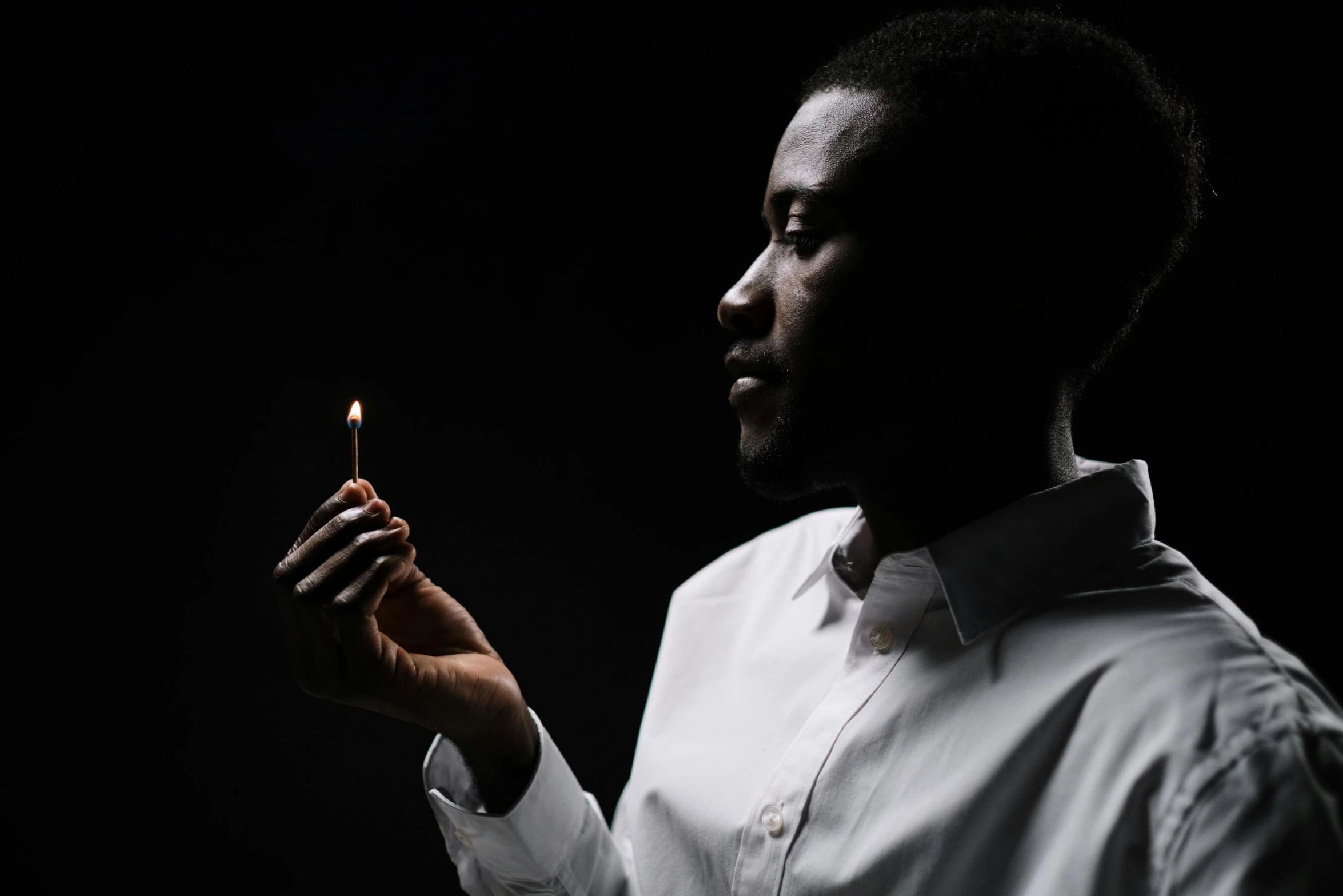 a man holding a lit candle in his hand, an album cover, pexels contest winner, hurufiyya, adebanji alade, looking to his side, play of light, promotional image