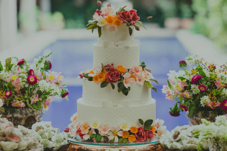 a wedding cake sitting on top of a table, unsplash, poolside, made of flowers, award-winning crisp details”, full faces